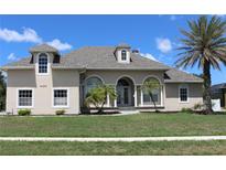 Charming single-Gathering home featuring arched entryways, lush lawn, and mature palm tree at 4150 Enclave Pl, Punta Gorda, FL 33980