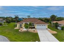 Inviting single-story home with a well-manicured lawn, palm trees, and a spacious driveway leading to an attached two-car garage at 7512 Pon Kan, Punta Gorda, FL 33955