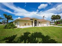 Charming single-story home featuring a well-manicured lawn, a garden, and mature palm trees at 1 Sportsman Cir, Rotonda West, FL 33947