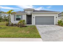 Charming one-story home featuring gray exterior paint, a paved driveway, and a two-car garage at 11088 Pinot Dr, Venice, FL 34293