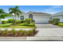 Charming single-story home featuring a well-manicured lawn, tropical landscaping, and a paver driveway at 16176 Lotus Way, Punta Gorda, FL 33982