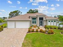 Beautiful single-story home with a three-car garage, charming front garden, and welcoming seating area at 1721 Walden Ct, Englewood, FL 34224
