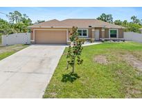 Inviting single-story home with a well-manicured lawn, a two-car garage, and mature landscaping at 3138 Darius Ave, North Port, FL 34288