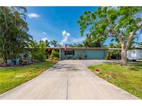 Charming single-story home with blue exterior paint, a driveway, and lush tropical landscaping at 611 Bonita Ct, Punta Gorda, FL 33950