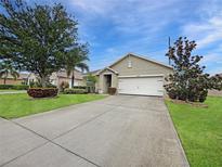 Well-maintained front yard featuring lush landscaping and a spacious driveway leading to a two-car garage at 7292 Mikasa Dr, Punta Gorda, FL 33950