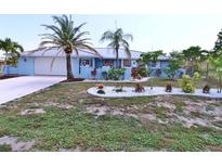 Charming blue single-story home featuring a metal roof, lush landscaping, and a well-manicured lawn at 107 Sinclair Se St, Port Charlotte, FL 33952
