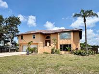 Two story home showcasing a front yard with a two car garage, trees and tropical foliage at 1611 Robbins Rd, Nokomis, FL 34275