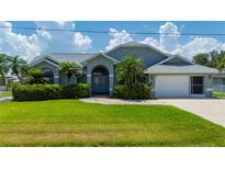 Well-maintained home with vibrant green lawn, mature landscaping, and an arched entryway, exuding curb appeal at 25371 Paladin Ln, Punta Gorda, FL 33983