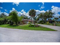 Charming single-story home with a well-manicured front yard, mature trees, and a circular driveway at 3960 Magara Ter, North Port, FL 34287
