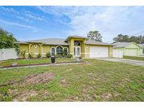 Charming single-story home with a well-manicured lawn and a two-car garage under a bright blue sky at 4413 S San Mateo Dr, North Port, FL 34288