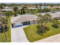 Inviting waterfront home with lush landscaping, screened in porch, and a long concrete driveway at 444 Edgewood Rd, Venice, FL 34293