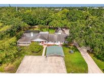 Expansive single-story home featuring lush landscaping, a covered pool, and a detached garage surrounded by mature trees at 4511 Wilkinson Rd, Sarasota, FL 34233