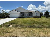 Charming single-story home featuring a lush green lawn, a two car garage, and a beautifully landscaped front yard at 9469 Spring Cir, Port Charlotte, FL 33981