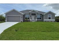 Charming gray single-story home with well-manicured lawn and attached two-car garage at 10023 Greetings St, Port Charlotte, FL 33981