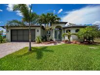 Charming home with a well-manicured lawn, brick driveway, and tropical landscaping at 13471 Chenille Dr, Port Charlotte, FL 33981