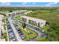 Community aerial view with beige condos, parking, and beautiful greenery under a partially cloudy blue sky at 175 Kings Hwy # 625, Punta Gorda, FL 33983