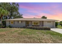 Charming single-story home with a well-maintained lawn and rock border at sunset at 18178 Wolbrette Cir, Port Charlotte, FL 33948