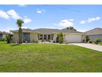 Charming single-story home featuring a well-manicured lawn and tropical landscaping at 26125 Copiapo Cir, Punta Gorda, FL 33983
