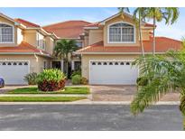 Inviting two-story home with a red tile roof, two-car garage, manicured landscaping, and brick-paved driveway at 2630 Tarpon Cove Dr # 212, Punta Gorda, FL 33950