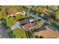 Aerial view of home featuring a private canal, screened pool, and lush landscaping at 372 Cory St, Port Charlotte, FL 33953