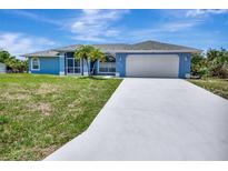 Charming single-story home with a two-car garage, well-maintained lawn, and freshly painted light blue exterior at 421 Strasburg Dr, Port Charlotte, FL 33954
