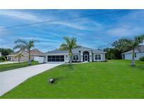 Charming single-story home featuring a well-manicured lawn and a long driveway lined with mature palm trees at 591 San Ambrosio St, Punta Gorda, FL 33983