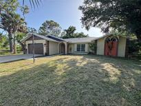 Charming single-story home with a well-manicured lawn, arched entryways, and attached two-car garage at 726 Chevy Chase St, Port Charlotte, FL 33948
