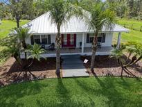 Charming single story home with a metal roof, front porch, walkway, and mature landscaping at 7424 Acorn Blvd, Punta Gorda, FL 33982
