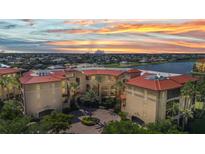 Beautiful aerial view of a multi-story residential building with a red tile roof, set against a vibrant sunset sky at 90 Vivante Blvd # 202, Punta Gorda, FL 33950