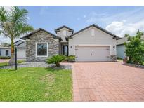 Charming single-Gathering home with a stone facade, brick driveway, and a well-manicured lawn at 15261 Mille Fiore Blvd, Port Charlotte, FL 33953