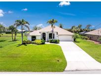 Charming single-story home featuring lush lawn, palm trees and a pristine driveway at 167 & 169 Marker Rd, Rotonda West, FL 33947
