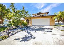 Charming home with a two-car garage, palm trees, and mature landscaping at 18566 Arapahoe Cir, Port Charlotte, FL 33948