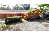 Inviting one-story home features an orange exterior, manicured shrubs, and a gravel driveway at 2131 Heasley Rd, Englewood, FL 34223