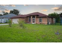 Tan single-story home featuring arched windows and a well-maintained front lawn at 23101 Hillsdale Ave, Port Charlotte, FL 33954