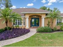 Inviting single-story home featuring double front doors, lush landscaping, and a brick walkway to the entrance at 2373 Chartwell Ave, North Port, FL 34288