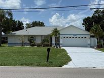 Charming single story home featuring an attached two-car garage and a well-manicured front lawn at 26312 Deep Creek Blvd, Punta Gorda, FL 33983