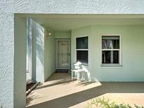 Inviting covered entrance with mint-green exterior, stylish wall lamp, and convenient small table near the door at 5725 Greenwood Ave # 5103, North Port, FL 34287
