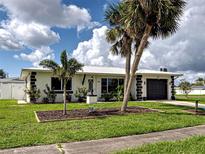 Charming single-story home with black and white accents, beautiful landscaping, and lush palm trees at 6483 Fabian Rd, North Port, FL 34287