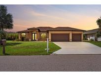Beautiful single-story home with a well-manicured lawn and a three-car garage on a sunny day at 1275 Blue Lake Cir, Punta Gorda, FL 33983