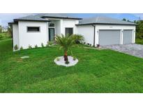 Well-manicured front yard featuring a young palm tree in a circular white rock bed with green grass at 14520 Edna Cir, Port Charlotte, FL 33981