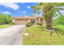 Charming single-story home with lush landscaping, mature palm trees, and a well-maintained lawn under a sunny, blue sky at 17125 Canary Ln, Port Charlotte, FL 33948
