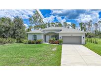 Charming single-story home with a well-manicured lawn, lush landscaping, and a neutral color scheme at 1722 Amnesty Dr, North Port, FL 34288