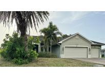 Charming single-story home featuring an attached two-car garage and lush landscaping with palm trees at 2143 Santonian Ter, North Port, FL 34286