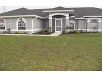 Charming single-story home featuring a well-manicured lawn, arched windows, and a screened-in entryway at 23167 Turnbull Ave, Port Charlotte, FL 33954