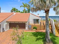 Beautiful waterfront home with a brown garage door, lush landscaping, and a wooden deck overlooking the water at 25188 Marion Ave # 45, Punta Gorda, FL 33950