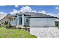 Charming blue single-Gathering home featuring a well-manicured lawn, beautiful flowerbeds, and a large two-car garage at 2815 Coral Way, Punta Gorda, FL 33950