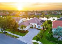 Beautiful aerial shot of a sun-drenched home with tile roof, lush landscaping, and a serene lake view in a lovely neighborhood at 4334 Corso Venetia Blvd, Venice, FL 34293