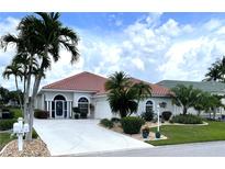 Charming single-story home features a red tile roof, mature landscaping, and a pristine driveway at 10214 Arrowhead Dr, Punta Gorda, FL 33955