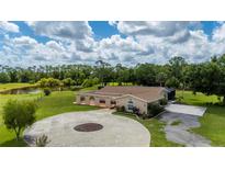 Expansive home featuring a circular driveway, screened in lanai, and tranquil lake views amidst lush landscaping at 10810 Wheeler Pl, Punta Gorda, FL 33950