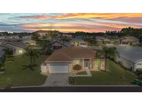 Charming single-story home featuring a well-maintained lawn, attached garage, and tropical landscaping under a beautiful sunset at 1605 Palace Ct, Punta Gorda, FL 33980